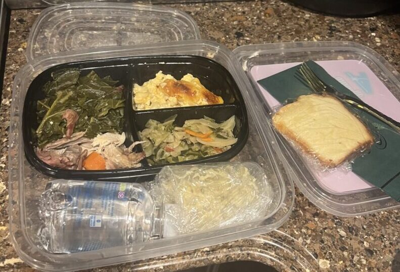 A meal in a container with some bread and vegetables