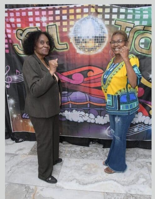 Two women standing next to each other in front of a poster.