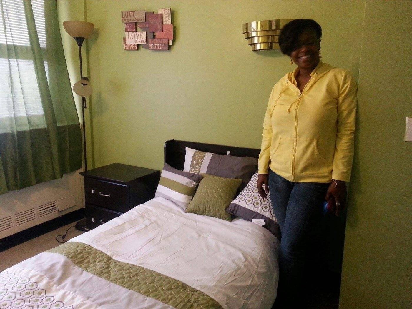 A woman standing in front of a bed with pillows on it.