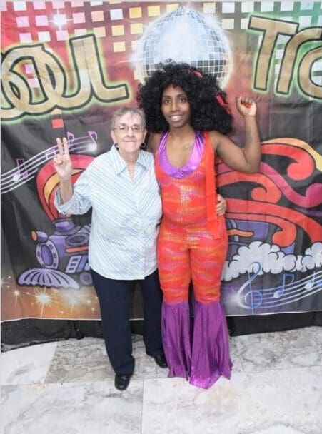 A woman in an orange outfit standing next to another person.