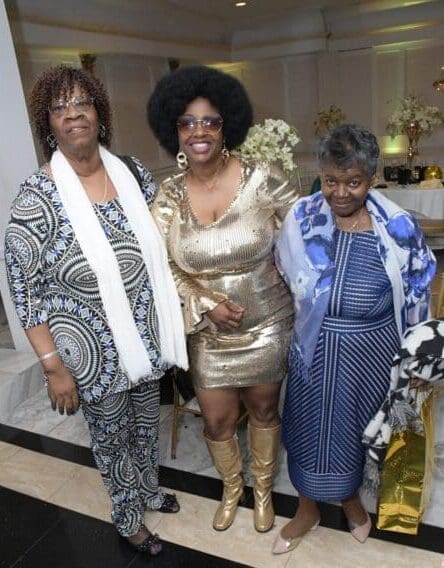 Three women standing next to each other in a room.