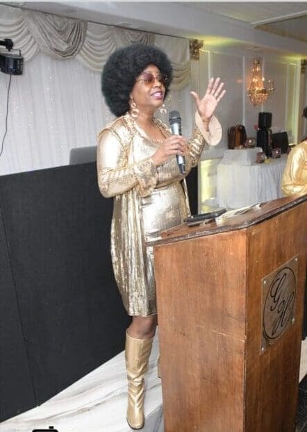 A woman in gold dress standing at a podium.