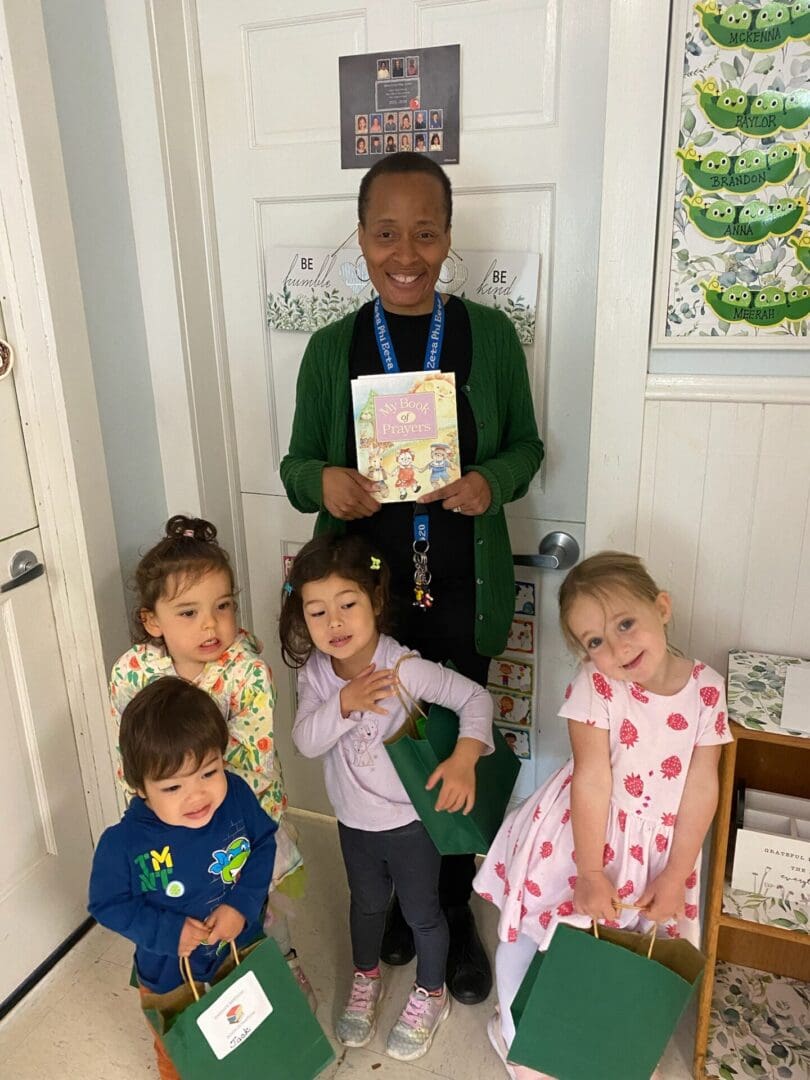 A woman holding a book with children in front of her.