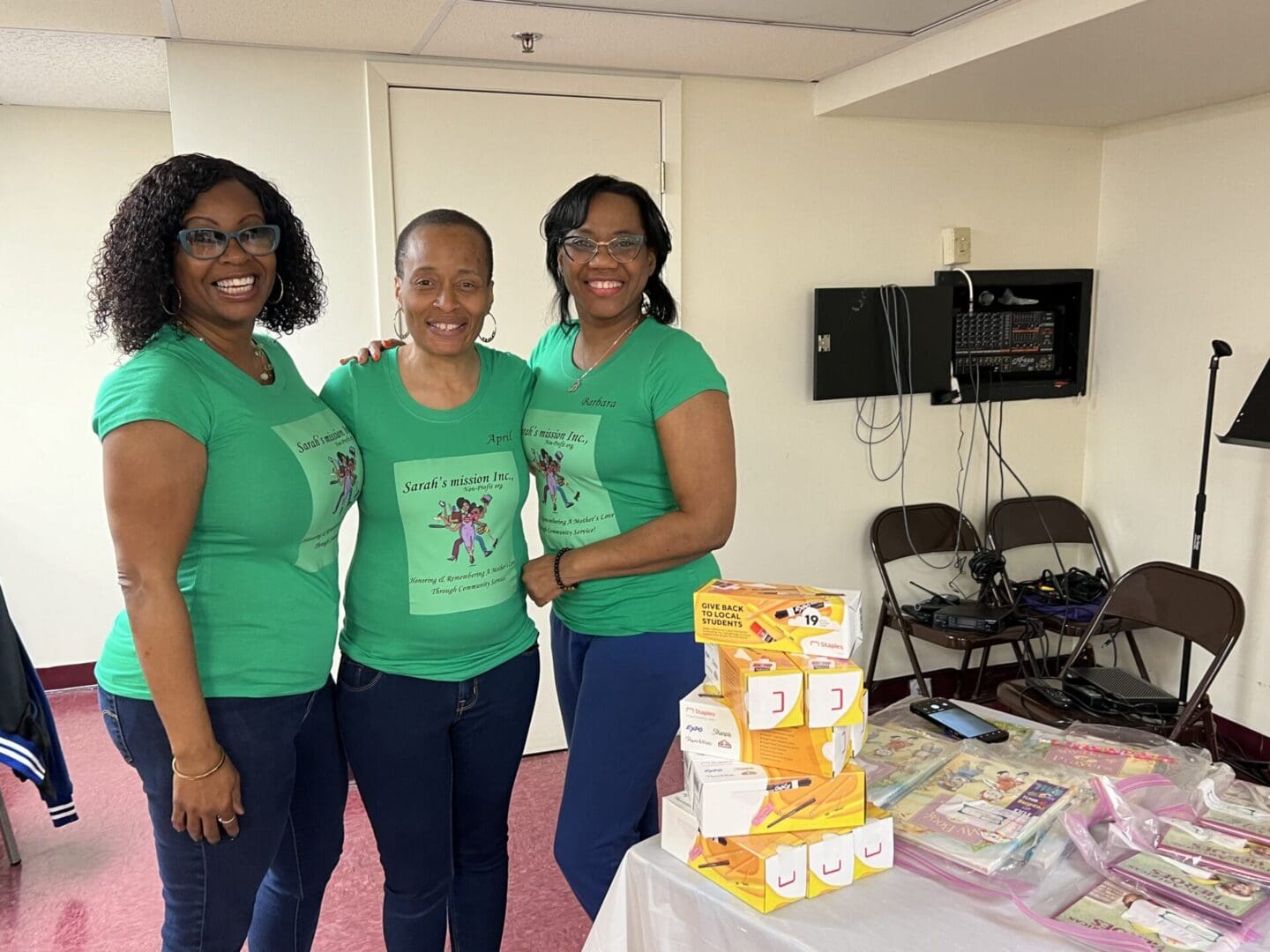 Three women standing in a room with boxes.