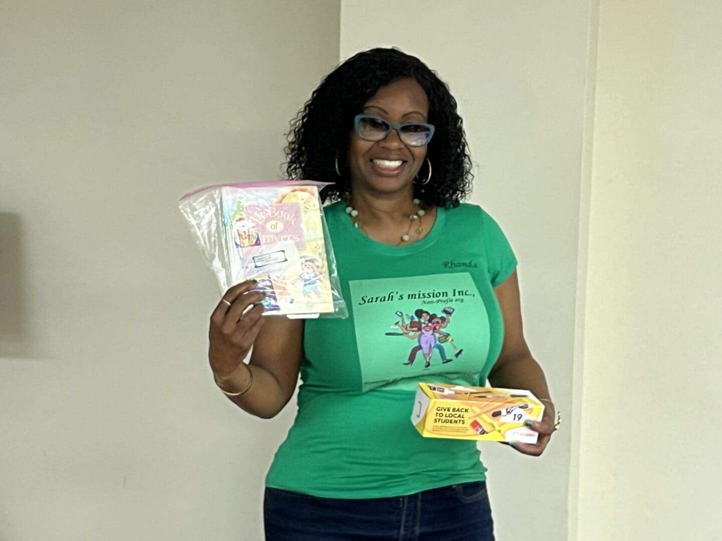 A woman holding up two books and an envelope.