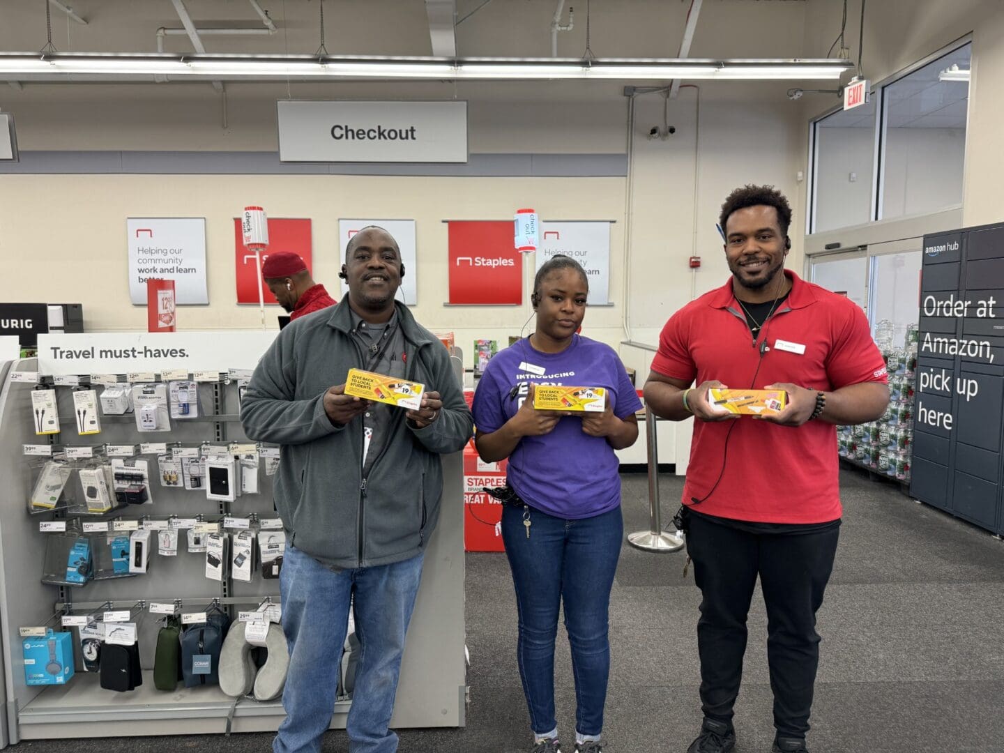 Three people holding up boxes in a store.