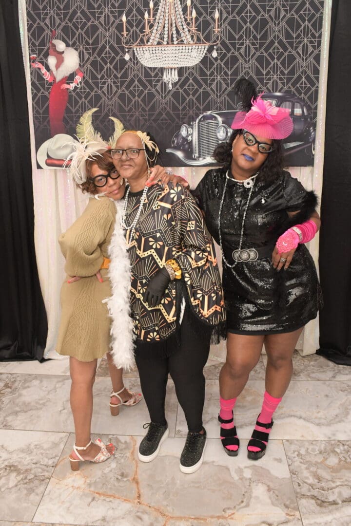 Three women posing for a picture in front of a wall.