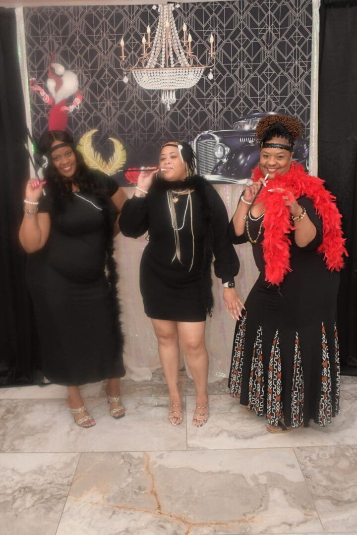 Three women posing for a picture in front of a black background.