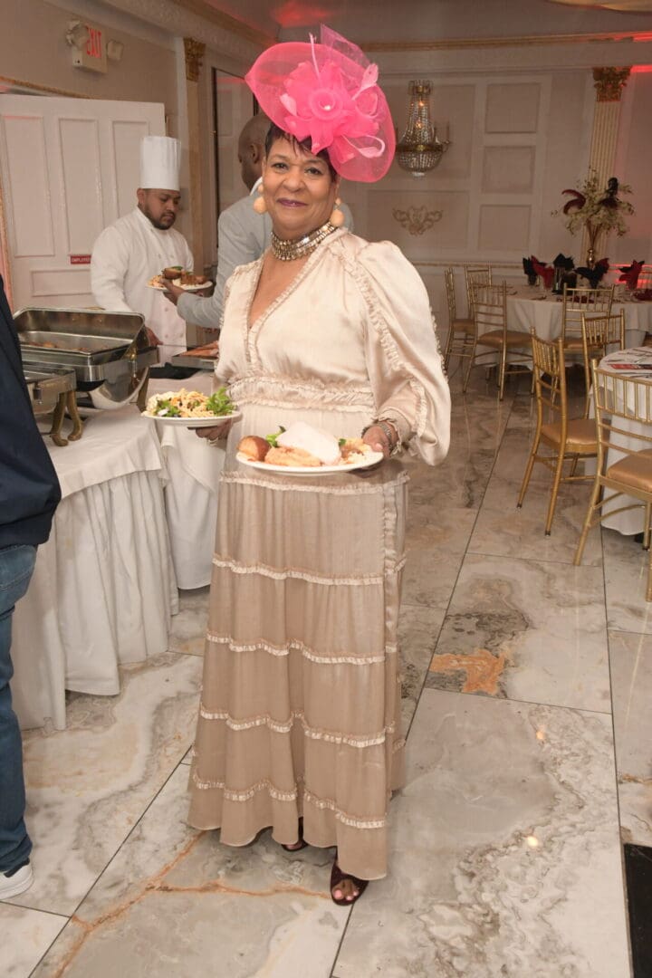 A woman in a long dress holding a plate of food.