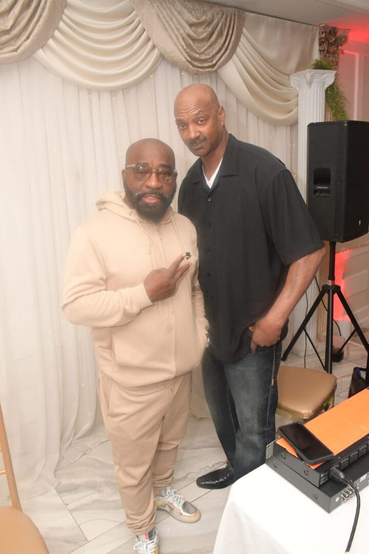 Two men posing for a picture in front of a speaker.