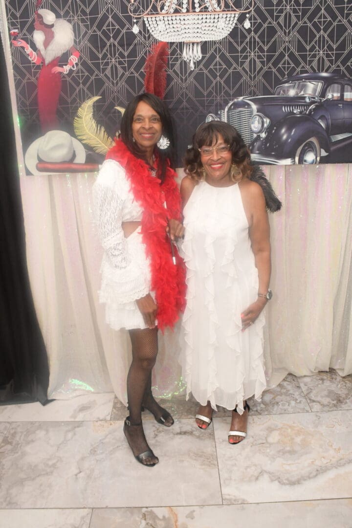 Two women in white dresses posing for a picture.