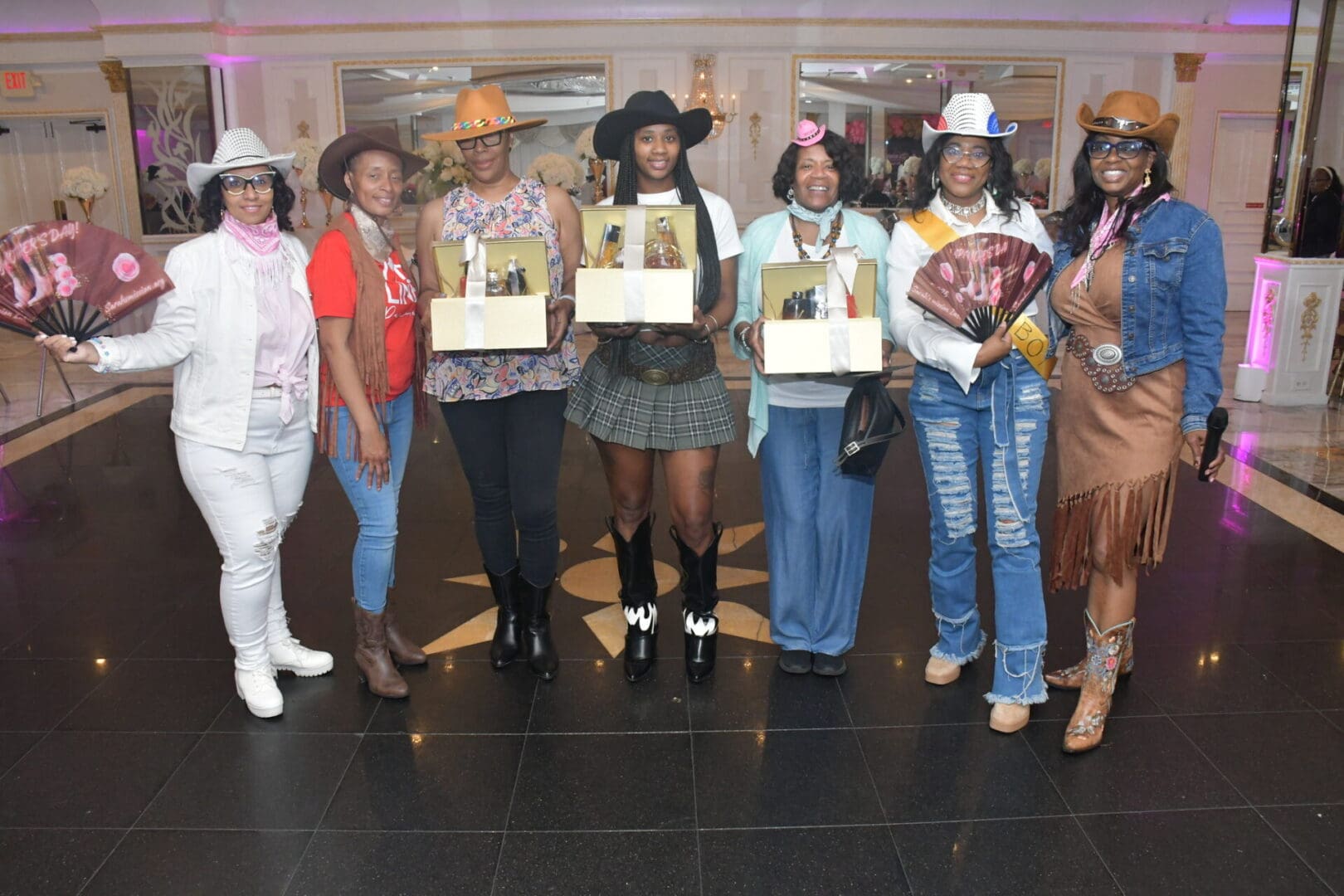 Seven women in cowboy-themed outfits smiling.