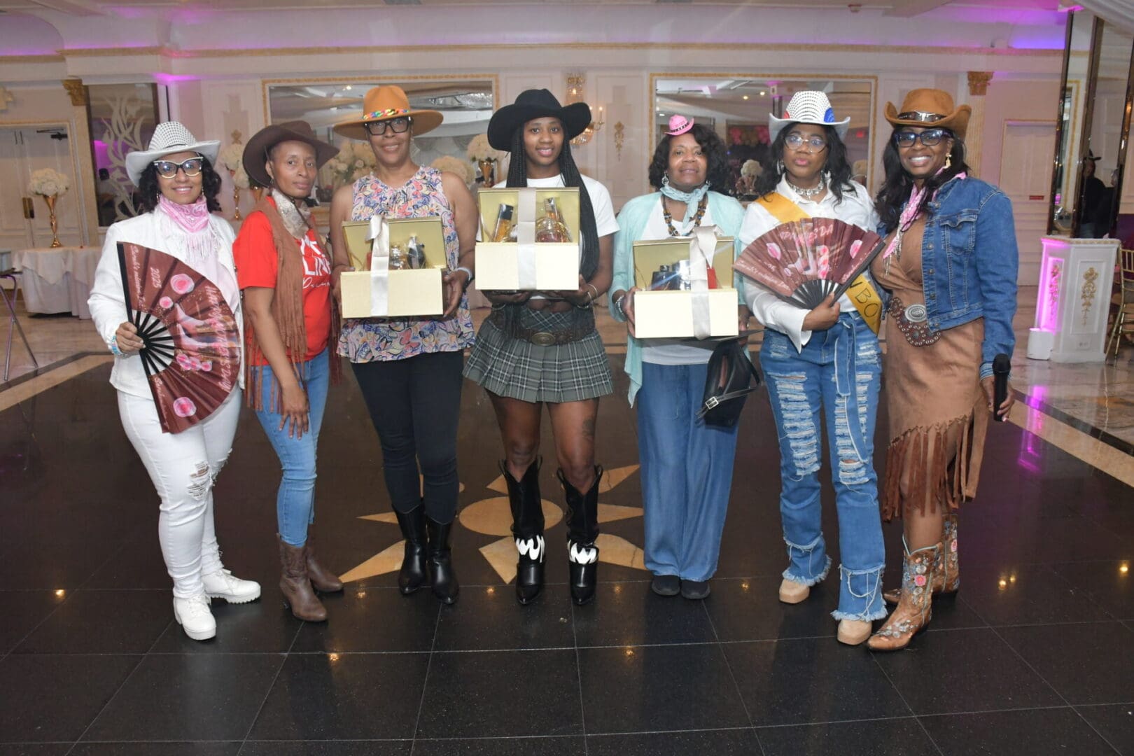 Seven women in cowboy hats holding awards.