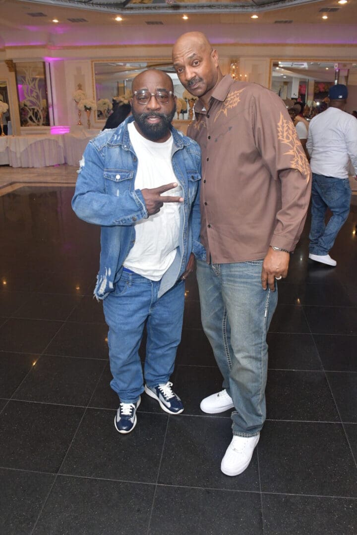 Two men posing in casual clothes indoors.