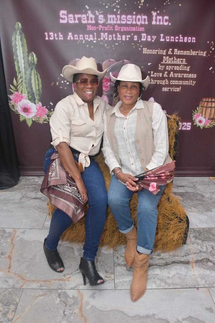 Two women in cowboy hats, smiling together.