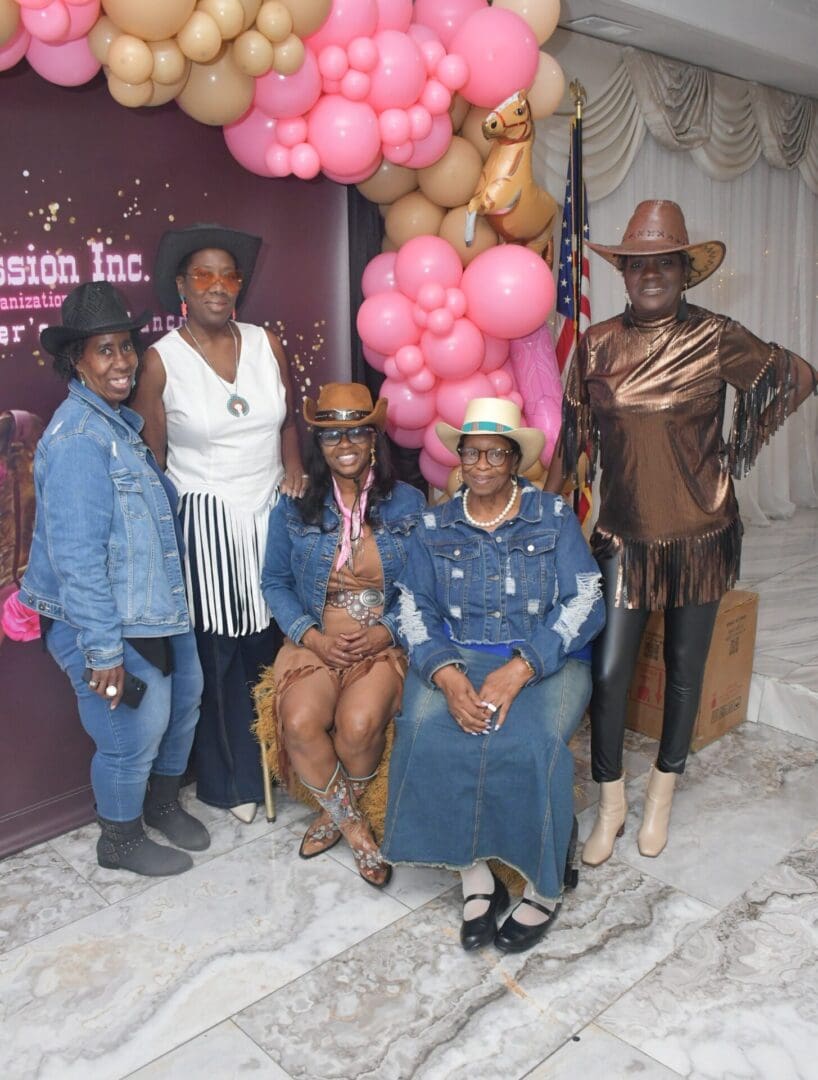 Group in cowboy hats with balloon backdrop.