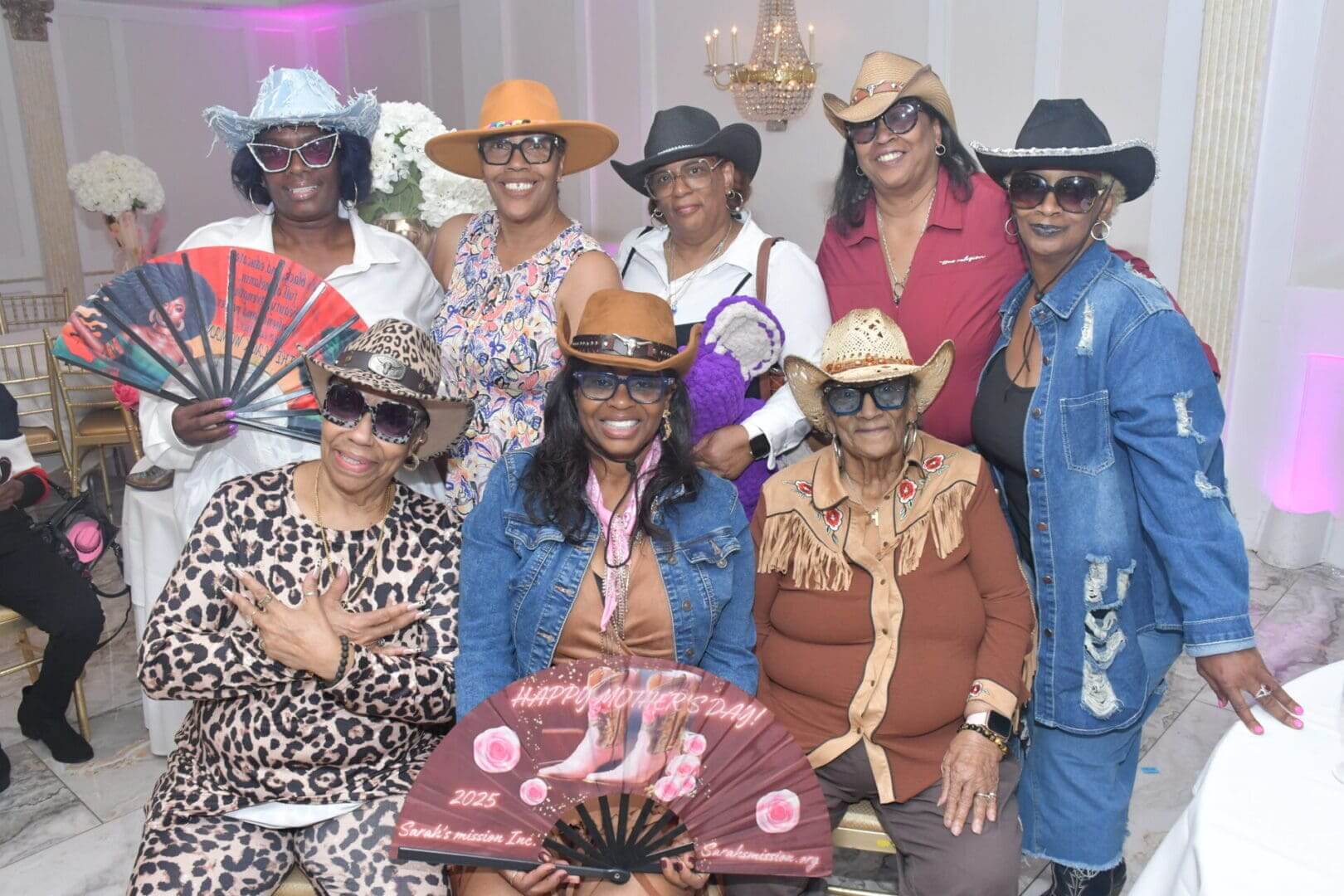 Group of women in cowboy hats smiling.