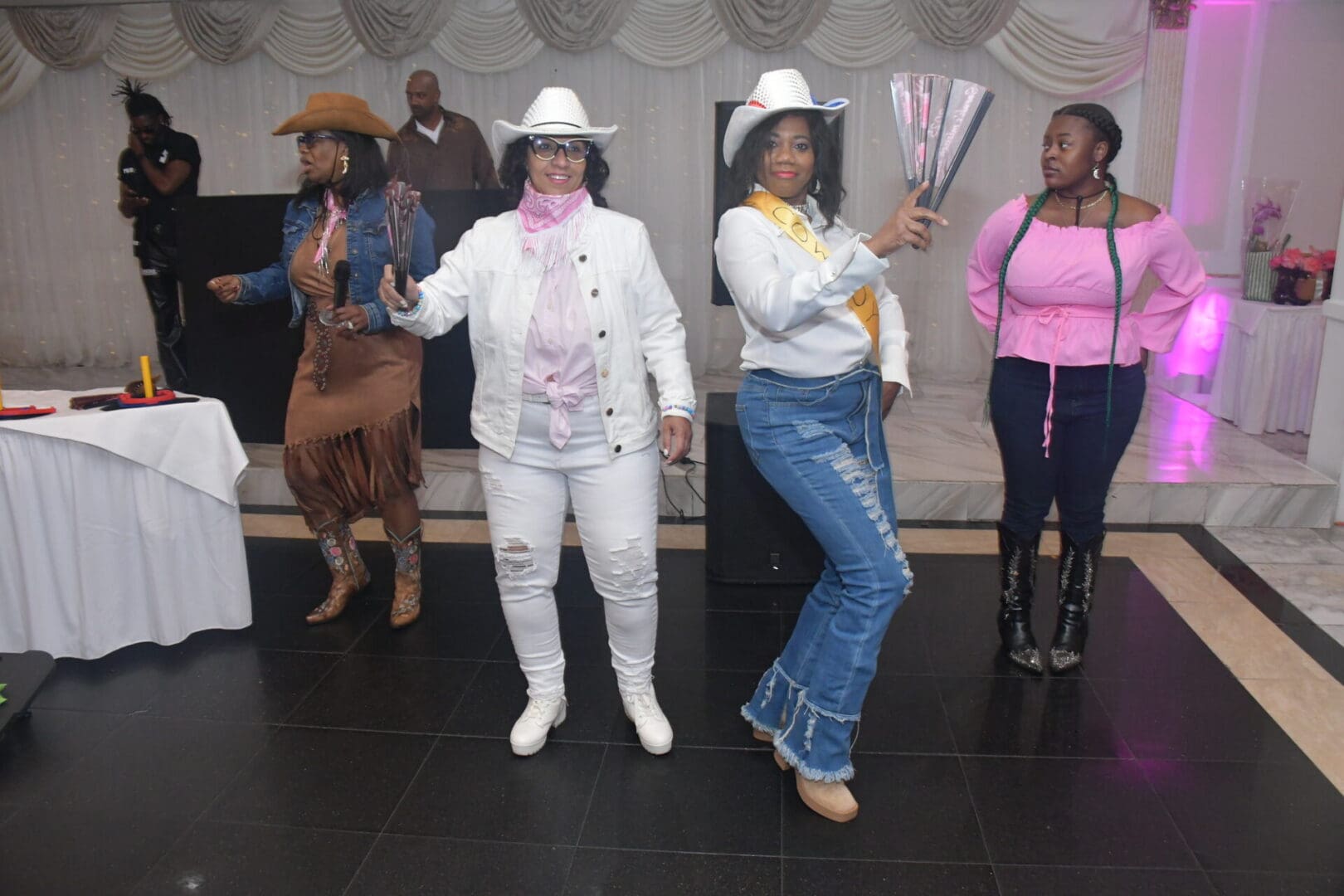 Women in cowboy-themed attire dancing indoors.