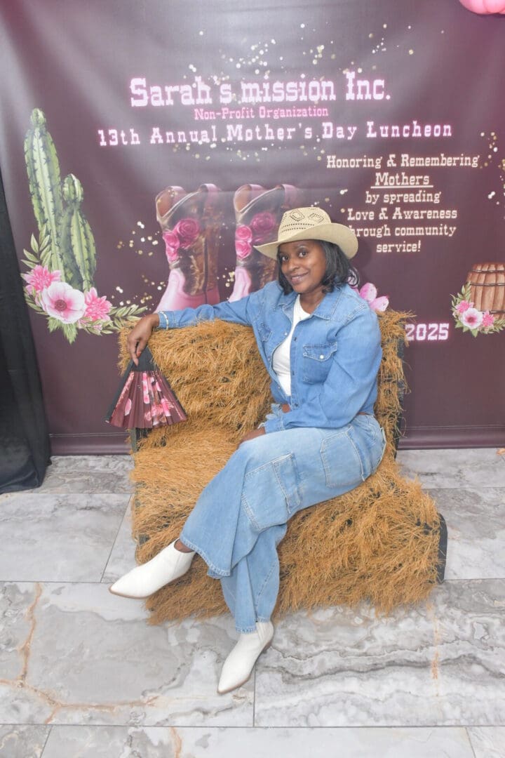 Woman in denim outfit sitting on hay.