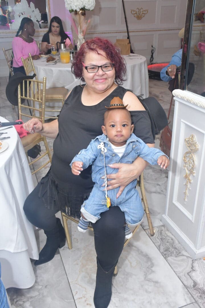 Woman holding baby at a dining event.