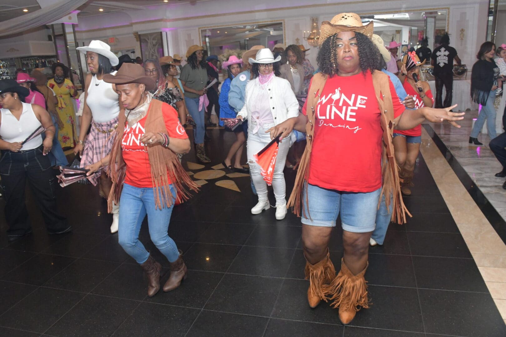 People line dancing in cowboy attire indoors.