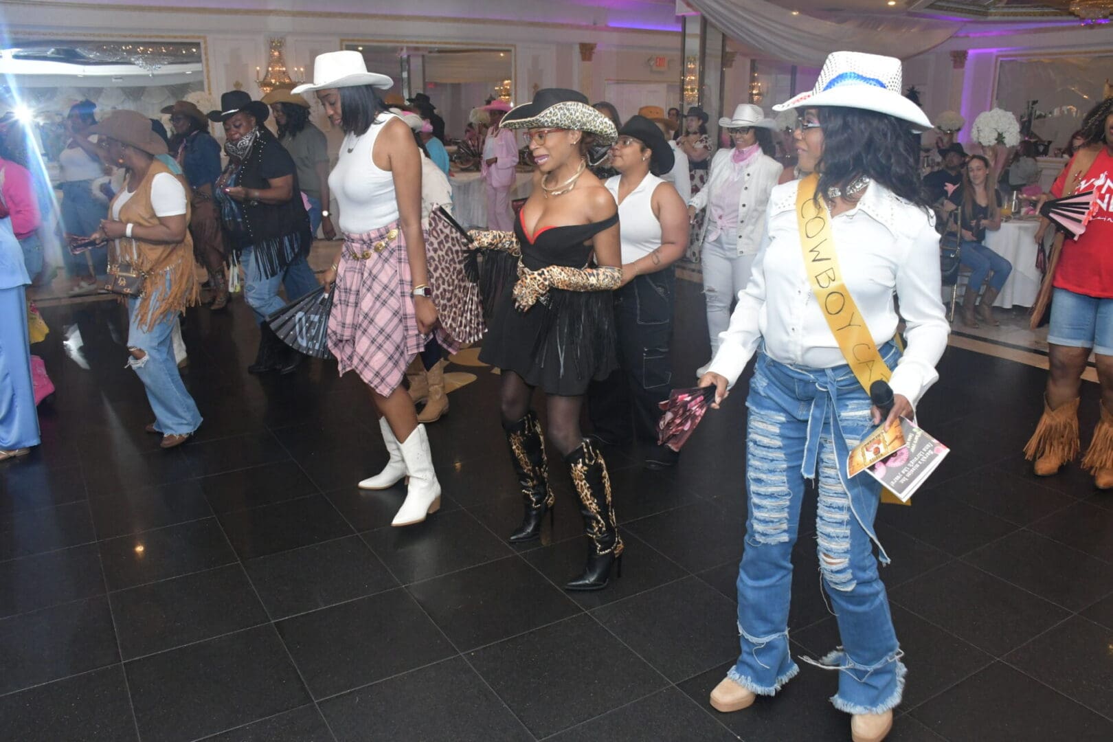 Line dancing in cowboy-themed outfits indoors.