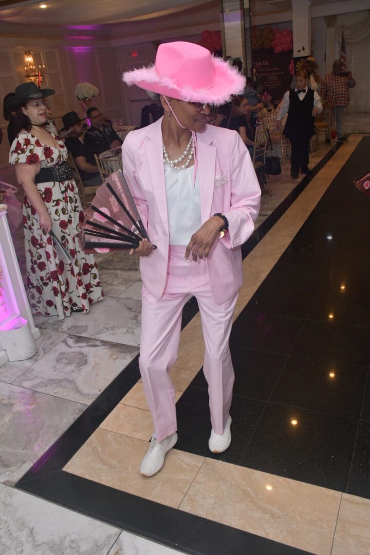 Person in pink suit and hat dancing.