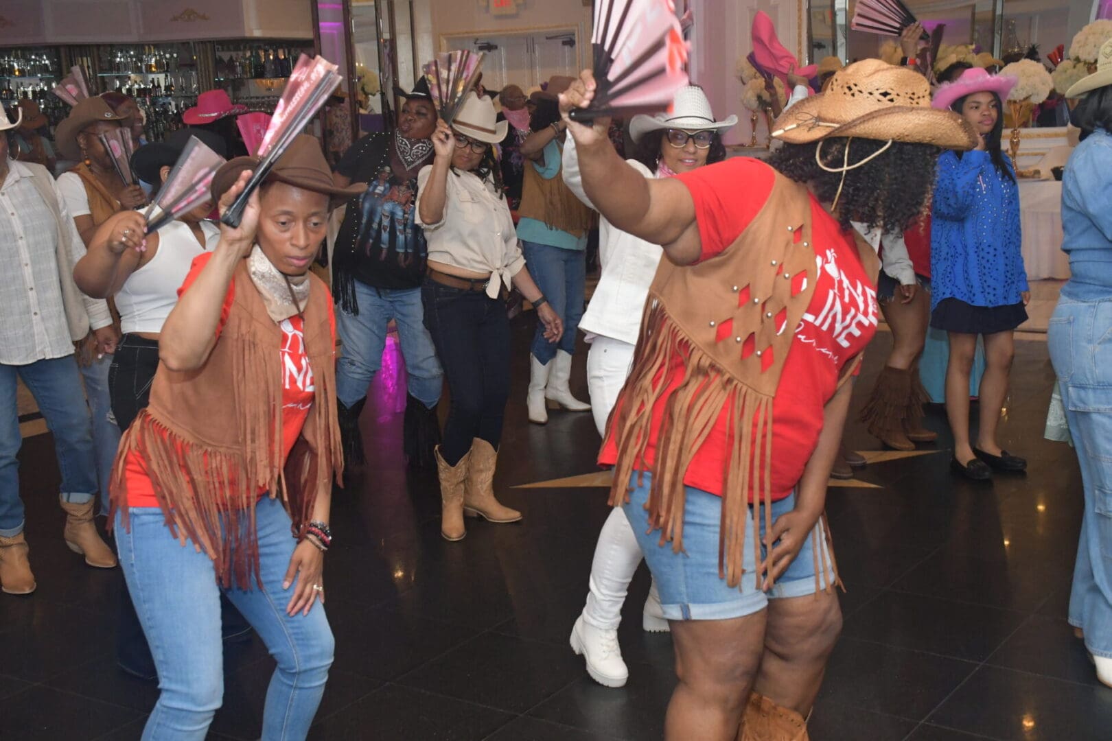 Line dancing group wearing cowboy hats indoors.