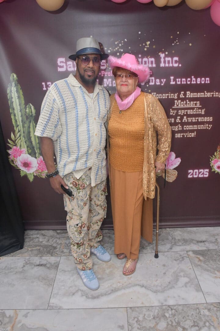 Man and woman posing at event backdrop.