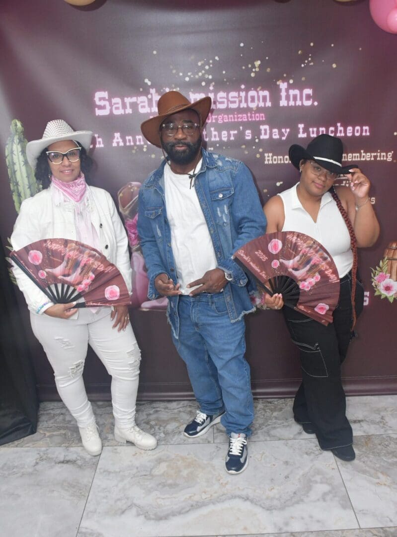 Three people posing with fans and hats.