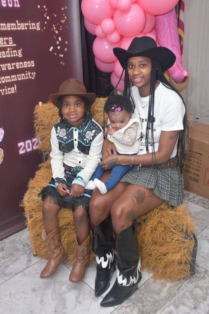 Family in cowboy hats sitting on hay.