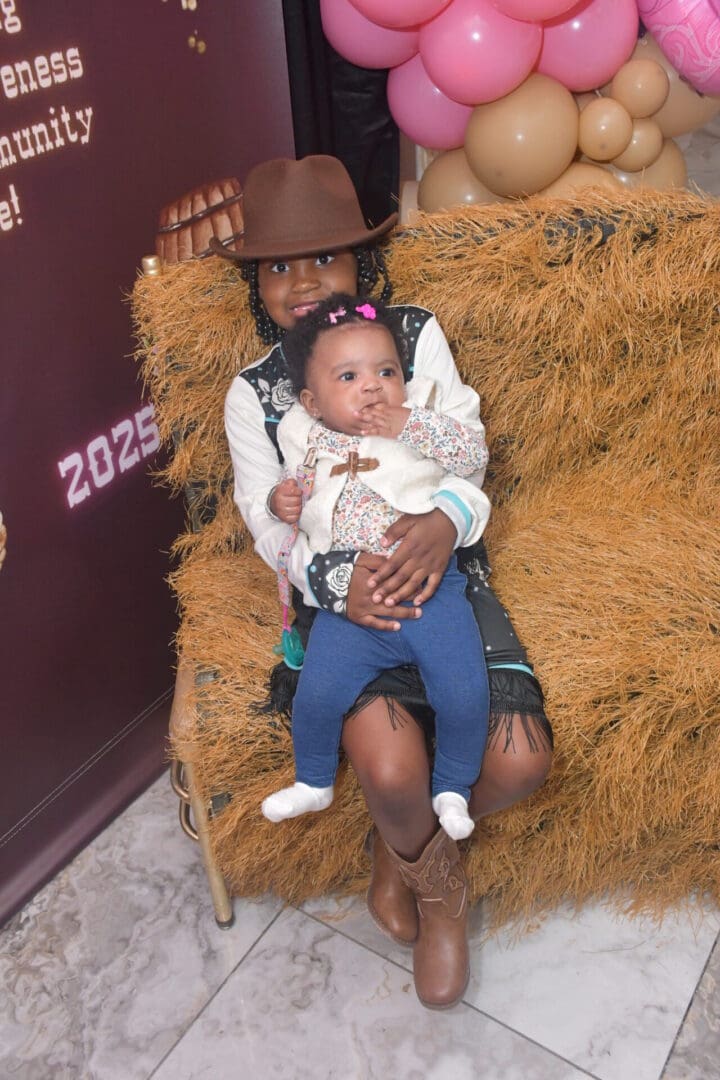 Child holding baby on straw seat.