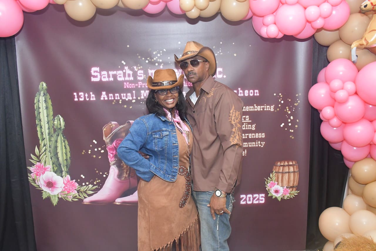 Couple posing at western-themed event backdrop.