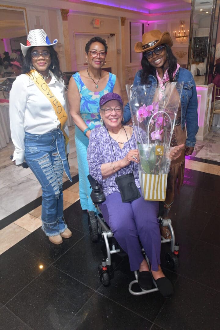 Four women posing at a festive event.