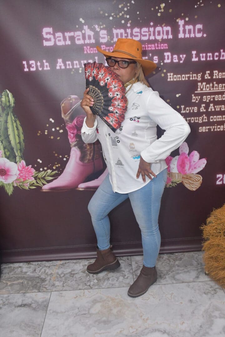 Person posing with fan and hat indoors.